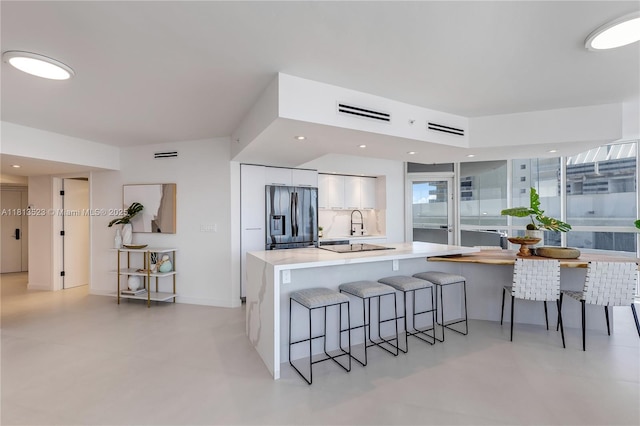 6301 Collins Ave Unit 1405, Miami Beach, FL 33141 - kitchen featuring refrigerator with ice dispenser, white cabinetry, a breakfast bar area, modern cabinets, and light countertops