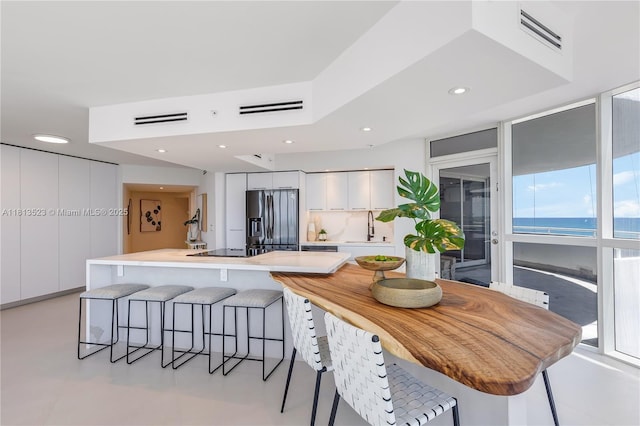 6301 Collins Ave Unit 1405, Miami Beach, FL 33141 - kitchen with stainless steel fridge with ice dispenser, white cabinetry, a kitchen breakfast bar, modern cabinets, and recessed lighting