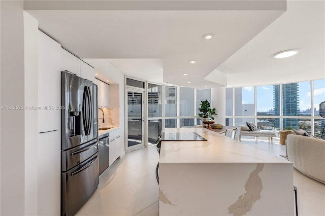 6301 Collins Ave Unit 1405, Miami Beach, FL 33141 - kitchen featuring stainless steel appliances, modern cabinets, white cabinetry, a kitchen island, and expansive windows