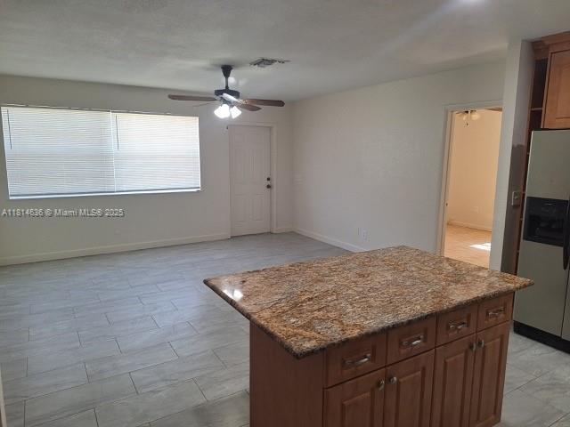 3961 Park Ln, Palm Springs, FL 33406 - kitchen featuring stainless steel refrigerator with ice dispenser, a ceiling fan, a center island, and stone countertops