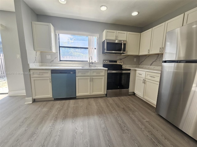4131 NW 79th Ave Unit 4131, Sunrise, FL 33351 - kitchen featuring stainless steel appliances, light countertops, a sink, light wood finished floors, and backsplash