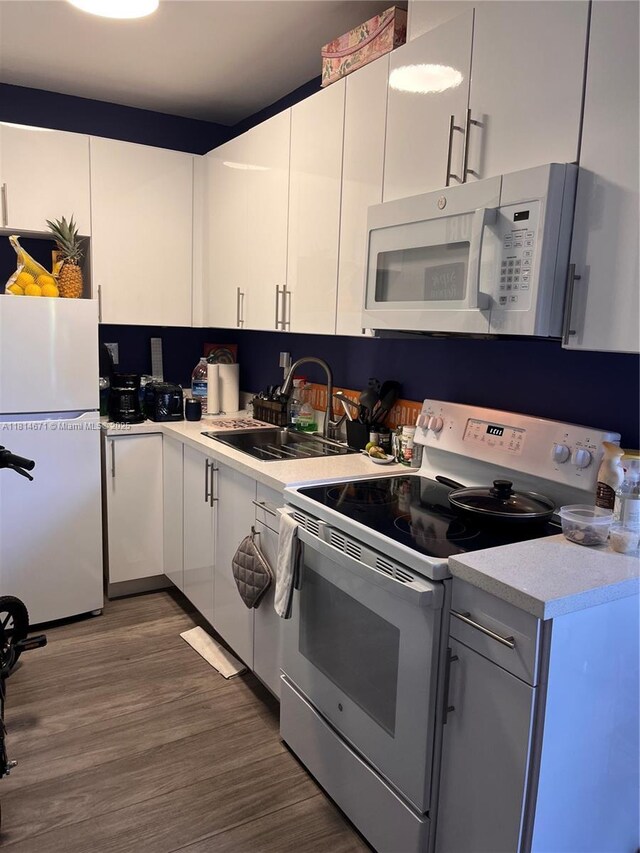 1105 NE 119th St, Biscayne Park, FL 33161 - kitchen featuring white appliances, light countertops, dark wood-type flooring, and white cabinets