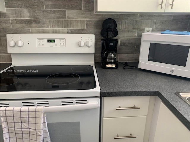 1105 NE 119th St, Biscayne Park, FL 33161 - kitchen view of white appliances, white cabinetry, dark countertops, and decorative backsplash