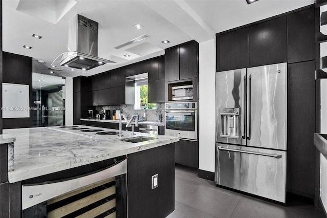 2612 Key Largo Ln, Fort Lauderdale, FL 33312 - kitchen featuring appliances with stainless steel finishes, dark cabinetry, island range hood, beverage cooler, and tasteful backsplash