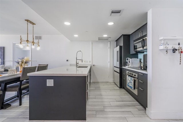 50 Biscayne Blvd Unit 3106, Miami, FL 33132 - kitchen with stainless steel appliances, a sink, light countertops, a kitchen island with sink, and dark cabinetry