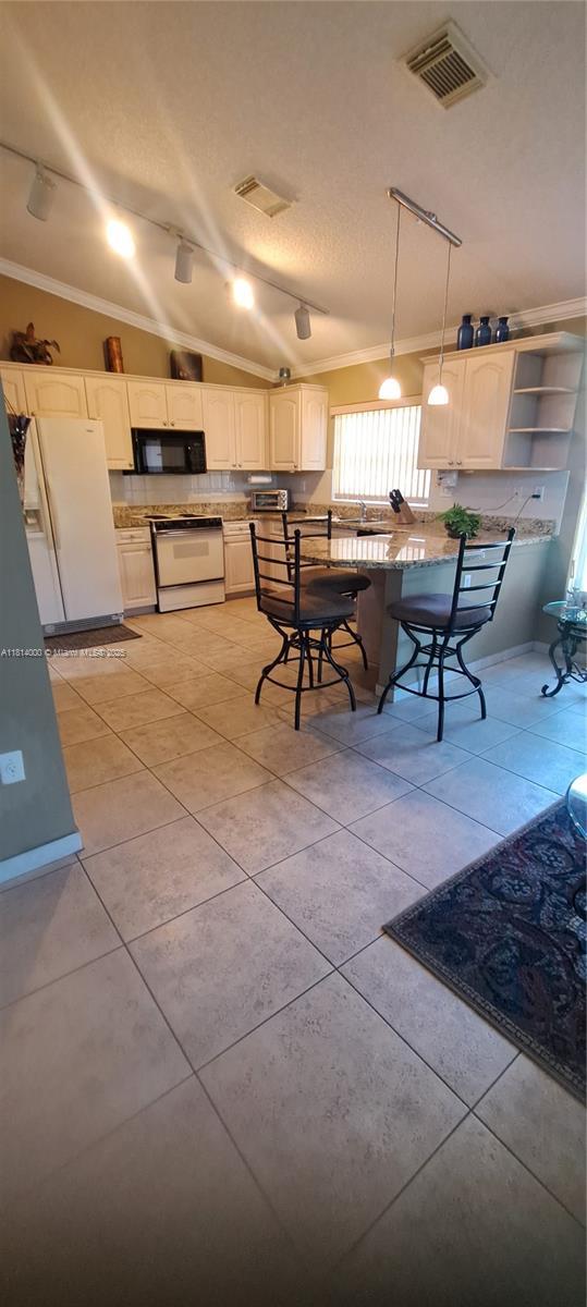 520 NW 166th Ave, Pembroke Pines, FL 33028 - kitchen featuring white range oven, ornamental molding, black microwave, track lighting, and decorative light fixtures