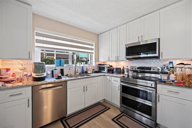 2649 SE 19th Ct Unit 106-D, Homestead, FL 33035 - kitchen with appliances with stainless steel finishes, a sink, tasteful backsplash, white cabinets, and a textured ceiling