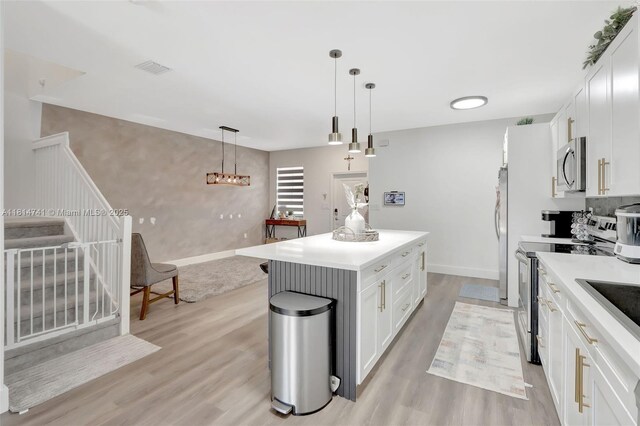 24686 SW 119th Pl, Homestead, FL 33032 - kitchen with appliances with stainless steel finishes, light wood-type flooring, light countertops, white cabinetry, and a center island
