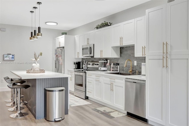 24686 SW 119th Pl, Homestead, FL 33032 - kitchen featuring stainless steel appliances, a sink, a breakfast bar area, light wood-style floors, and tasteful backsplash