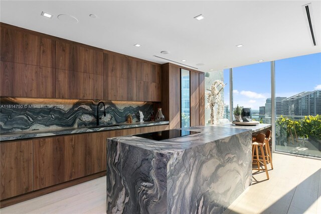 90 SW 3rd St Ph-14, Miami, FL 33130 - kitchen featuring modern cabinets, black electric stovetop, light wood-style flooring, a kitchen island, and tasteful backsplash