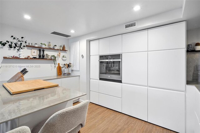 2150 Sans Souci Blvd Unit B311, North Miami, FL 33181 - kitchen with stainless steel oven, light wood-type flooring, white cabinets, open shelves, and modern cabinets