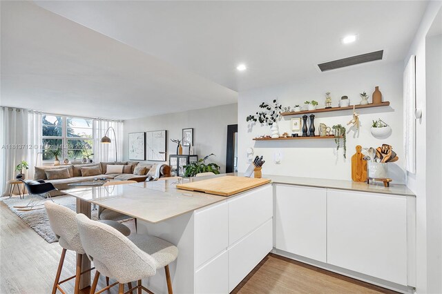 2150 Sans Souci Blvd Unit B311, North Miami, FL 33181 - kitchen with a peninsula, light wood-style flooring, white cabinets, light countertops, and a kitchen bar