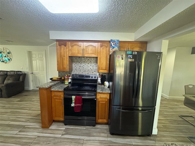 4706 25th Ave SW, Naples, FL 34116 - kitchen featuring freestanding refrigerator, range with electric cooktop, dark stone countertops, brown cabinetry, and a textured ceiling