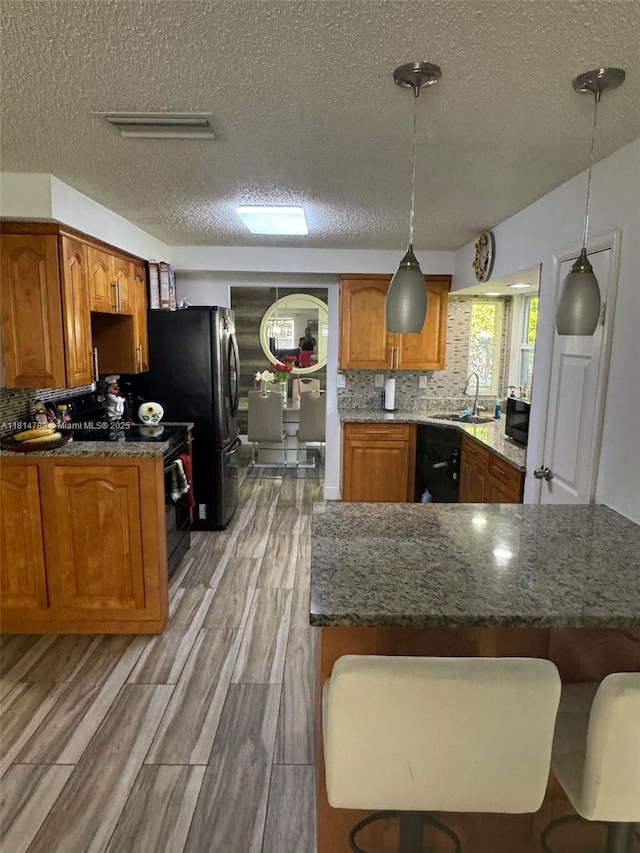 4706 25th Ave SW, Naples, FL 34116 - kitchen featuring a sink, a textured ceiling, black electric range oven, brown cabinets, and a peninsula