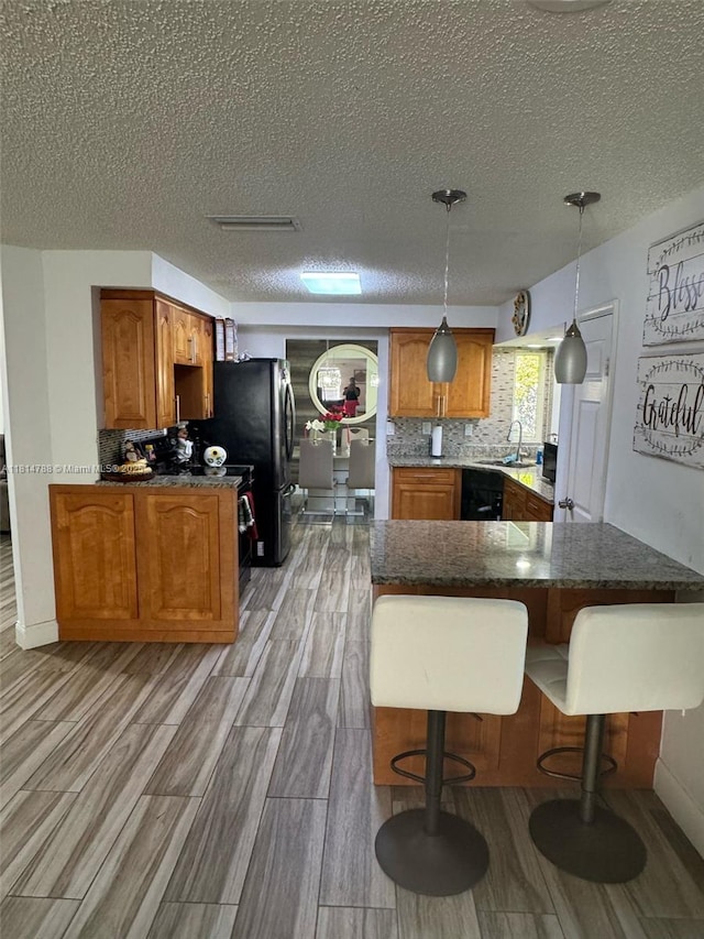 4706 25th Ave SW, Naples, FL 34116 - kitchen with tasteful backsplash, brown cabinetry, a textured ceiling, and light wood finished floors