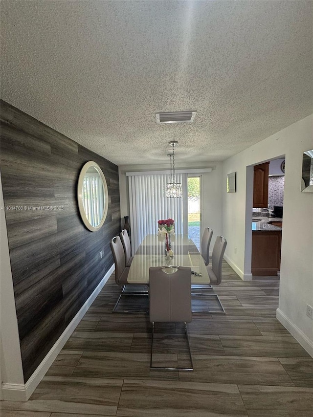 4706 25th Ave SW, Naples, FL 34116 - dining space with a chandelier, baseboards, an accent wall, wooden walls, and a textured ceiling