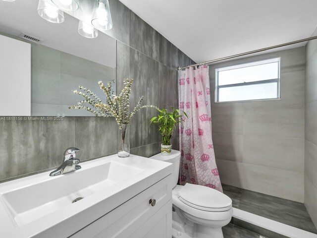 8401 Lagos De Campo Blvd Unit 210V, Tamarac, FL 33321 - bathroom with toilet, a tile shower, tile walls, and vanity