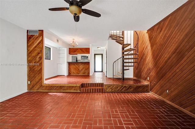 2591 Trapp Ave Unit 4, Miami, FL 33133 - unfurnished living room featuring wood walls, brick patterned floors, stairway, a chandelier, and baseboards