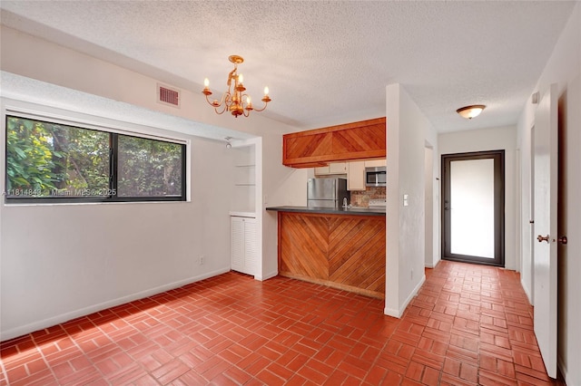 2591 Trapp Ave Unit 4, Miami, FL 33133 - kitchen with appliances with stainless steel finishes, a chandelier, baseboards, dark countertops, and a textured ceiling