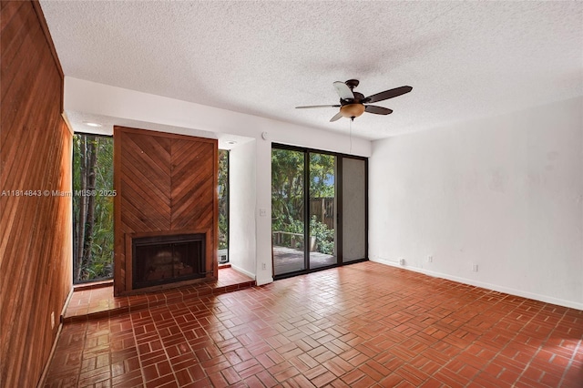 2591 Trapp Ave Unit 4, Miami, FL 33133 - unfurnished living room featuring a ceiling fan, baseboards, a large fireplace, and a textured ceiling