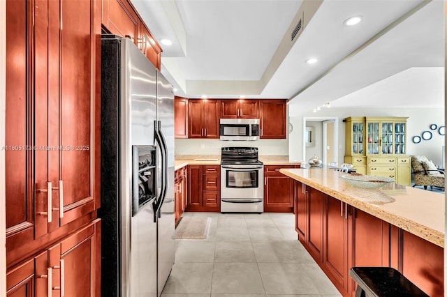 1410 S Ocean Dr Unit 502, Hollywood, FL 33019 - kitchen with appliances with stainless steel finishes, dark brown cabinets, light tile patterned floors, light stone counters, and a breakfast bar