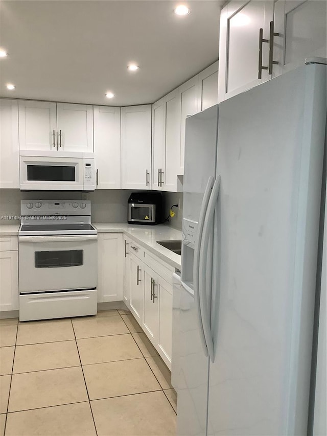 2333 Brickell Ave Unit 615, Miami, FL 33129 - kitchen with white appliances, white cabinetry, light tile patterned flooring, recessed lighting, and light countertops