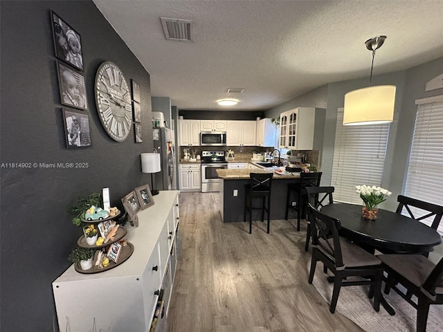 238 Magnolia Ave, Davie, FL 33325 - kitchen with appliances with stainless steel finishes, a peninsula, light wood-style floors, glass insert cabinets, and a sink