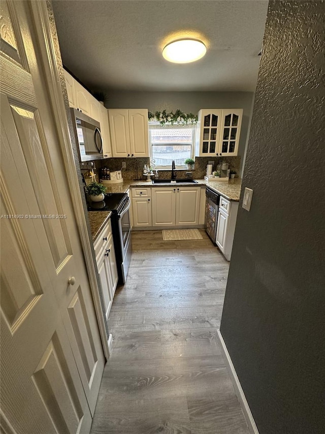 238 Magnolia Ave, Davie, FL 33325 - kitchen with appliances with stainless steel finishes, a sink, light wood-style floors, backsplash, and a textured wall