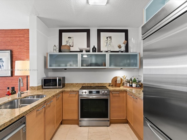 16275 Collins Ave Unit 2103, Sunny Isles Beach, FL 33160 - kitchen with stainless steel appliances, a sink, light stone countertops, glass insert cabinets, and a textured ceiling