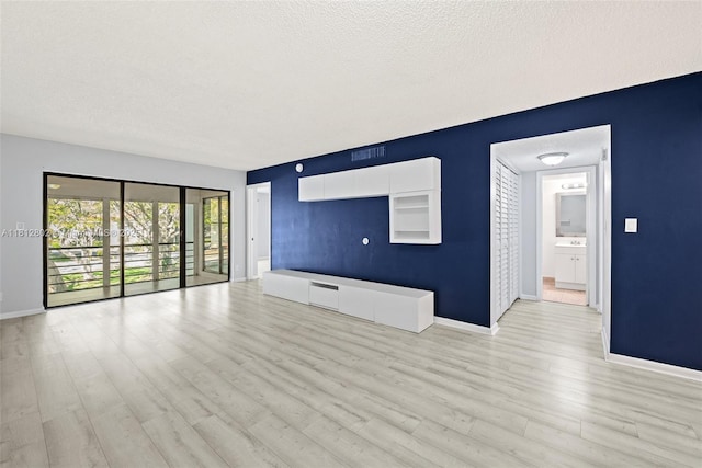 2302 S Cypress Bend Dr Unit 210, Pompano Beach, FL 33069 - unfurnished living room featuring light wood-style flooring, baseboards, and a textured ceiling