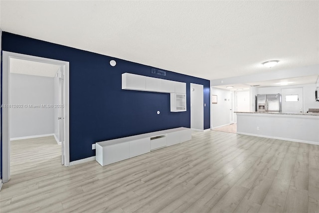 2302 S Cypress Bend Dr Unit 210, Pompano Beach, FL 33069 - unfurnished living room featuring light wood-type flooring, a textured ceiling, and baseboards