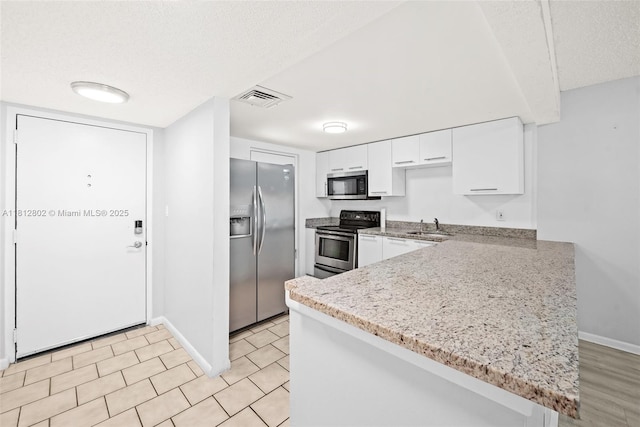 2302 S Cypress Bend Dr Unit 210, Pompano Beach, FL 33069 - kitchen with appliances with stainless steel finishes, a sink, white cabinetry, baseboards, and a peninsula