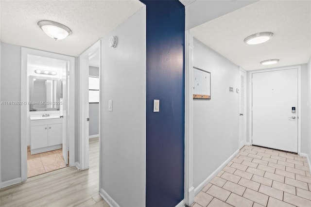 2302 S Cypress Bend Dr Unit 210, Pompano Beach, FL 33069 - hallway with a textured ceiling, a sink, and baseboards