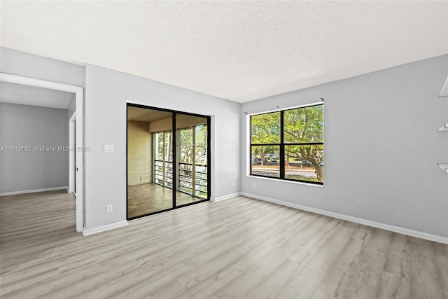 2302 S Cypress Bend Dr Unit 210, Pompano Beach, FL 33069 - empty room featuring wood finished floors, plenty of natural light, baseboards, and a textured ceiling