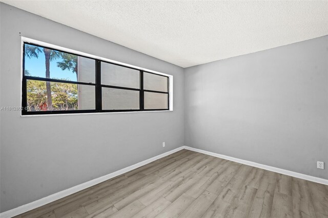 2302 S Cypress Bend Dr Unit 210, Pompano Beach, FL 33069 - unfurnished room featuring wood finished floors, baseboards, and a textured ceiling