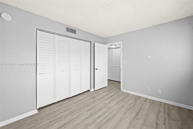 2302 S Cypress Bend Dr Unit 210, Pompano Beach, FL 33069 - unfurnished bedroom featuring wood finished floors, baseboards, a textured ceiling, and a closet