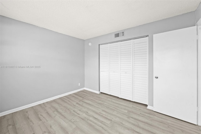 2302 S Cypress Bend Dr Unit 210, Pompano Beach, FL 33069 - unfurnished bedroom with wood finished floors, a closet, baseboards, and a textured ceiling