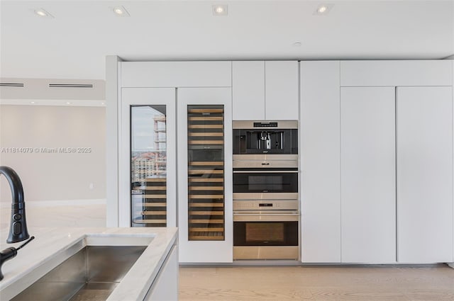 2200 N Ocean Blvd Unit S1801, Fort Lauderdale, FL 33305 - kitchen view of a sink, white cabinetry, light stone counters, modern cabinets, and beverage cooler