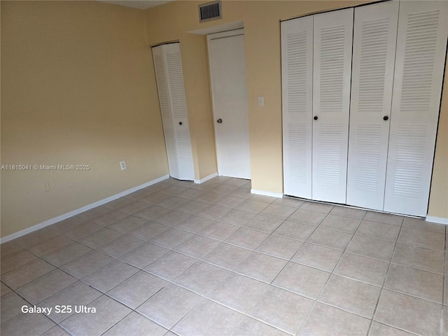 4102 W 10th Ln Unit 28, Hialeah, FL 33012 - unfurnished bedroom with light tile patterned floors, baseboards, and two closets