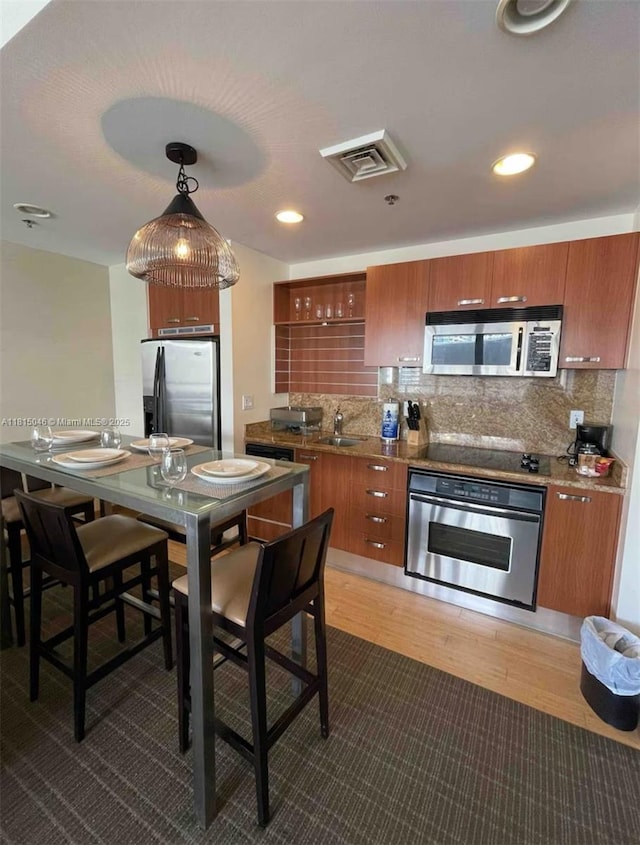 1395 Brickell Ave Unit 2814, Miami, FL 33131 - kitchen featuring appliances with stainless steel finishes, brown cabinets, backsplash, a sink, and recessed lighting