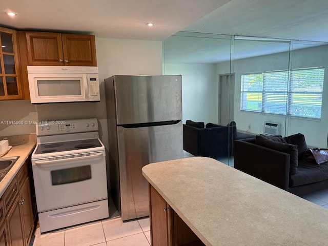 217 Suffolk F Unit 217, Boca Raton, FL 33434 - kitchen featuring white appliances, brown cabinetry, light tile patterned floors, open floor plan, and glass insert cabinets