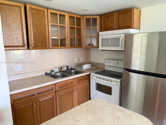 217 Suffolk F Unit 217, Boca Raton, FL 33434 - kitchen featuring white appliances, a sink, light countertops, brown cabinetry, and glass insert cabinets