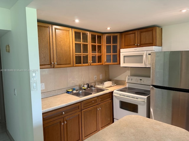 217 Suffolk F Unit 217, Boca Raton, FL 33434 - kitchen with white appliances, a sink, brown cabinetry, light countertops, and glass insert cabinets