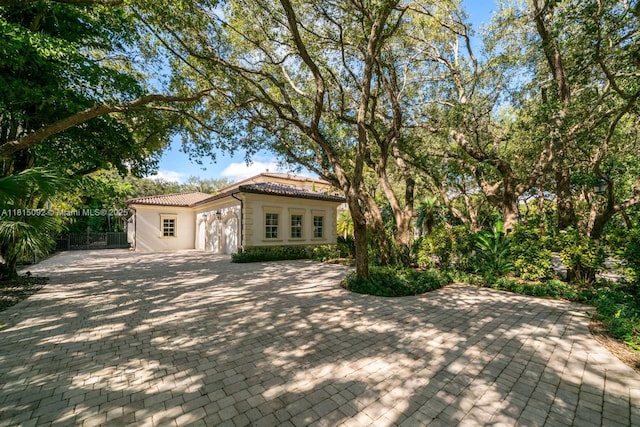 9500 SW 62nd Ct, Pinecrest, FL 33156 - mediterranean / spanish house featuring a tiled roof, a garage, decorative driveway, stucco siding, and a patio