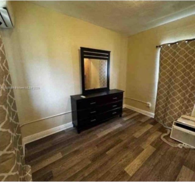 737 NW 6th St, Hallandale Beach, FL 33009 - unfurnished bedroom featuring dark wood-type flooring, an AC wall unit, and baseboards