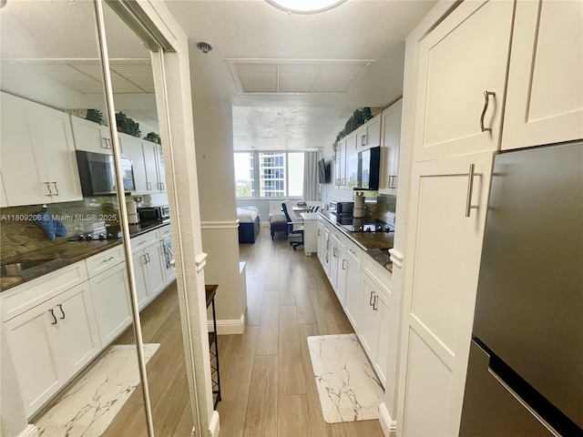 19201 Collins Ave Unit 427, Sunny Isles Beach, FL 33160 - kitchen featuring refrigerator, stainless steel microwave, white cabinetry, and light wood finished floors