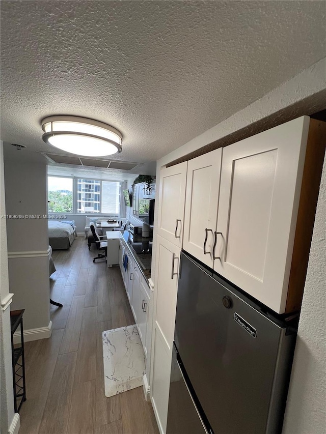 19201 Collins Ave Unit 427, Sunny Isles Beach, FL 33160 - kitchen featuring fridge, dark wood-type flooring, white cabinets, a textured ceiling, and open floor plan
