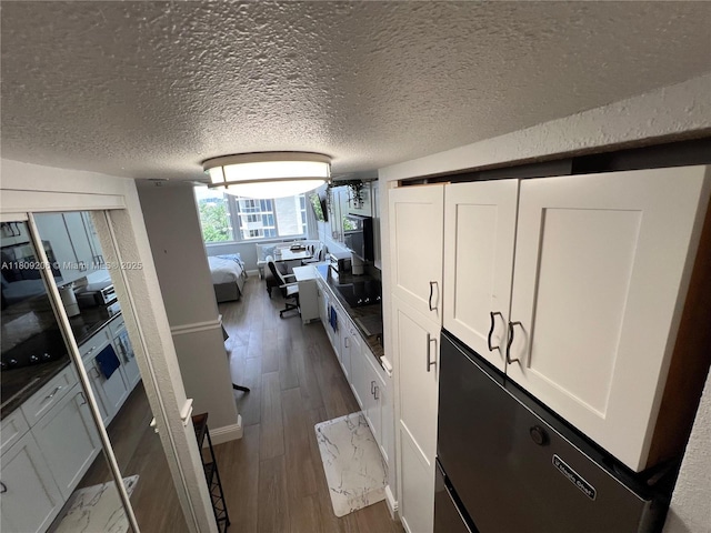 19201 Collins Ave Unit 427, Sunny Isles Beach, FL 33160 - kitchen with white cabinets, dark wood finished floors, a desk, fridge, and a textured ceiling