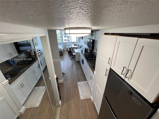 19201 Collins Ave Unit 427, Sunny Isles Beach, FL 33160 - kitchen with dark wood finished floors, a textured ceiling, white cabinets, black electric cooktop, and fridge
