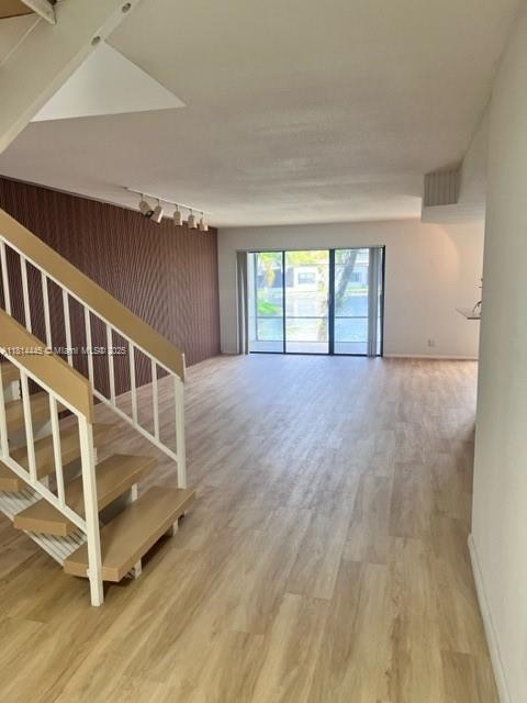 958 Mockingbird Ln Unit 511, Plantation, FL 33324 - unfurnished living room featuring track lighting, wood finished floors, stairs, and baseboards
